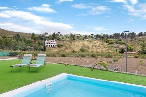 un patio trasero con piscina y 2 sillas en Villa Enora, en Las Palmas de Gran Canaria