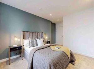 een slaapkamer met een groot bed en een blauwe muur bij Modern & Spacious Luxury Flat-10 min to London Eye in Londen