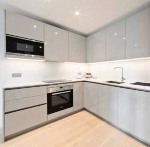 a kitchen with white cabinets and a sink and a stove at Modern & Spacious Luxury Flat-10 min to London Eye in London