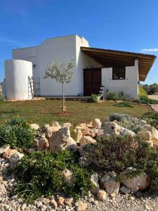 una casa con un árbol y rocas delante de ella en Residenza SA - tra mare e campagna, en Sannicola