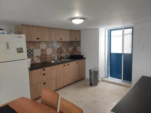 eine Küche mit einem Kühlschrank, einem Tisch und einem Fenster in der Unterkunft Lion's House in Kalymnos