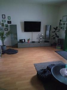 a living room with a flat screen tv and a wooden floor at Ferienwohnung Hoppe 2 in Pattensen