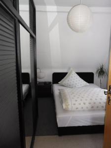 ein Schlafzimmer mit einem weißen Bett und einer Hängeleuchte in der Unterkunft Karin's behagliche Ferienwohnung in Benshausen