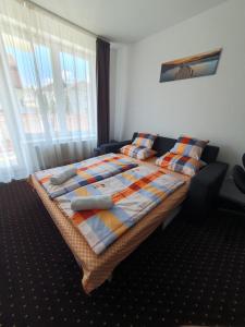 een slaapkamer met een bed met kussens en een raam bij Plage Carpe Diem 2 Apartman in Hajdúszoboszló