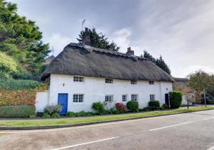 une vieille maison blanche avec un toit de chaume dans une rue dans l'établissement Thatch Cottage, à Shoreham-by-Sea