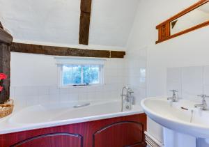 La salle de bains est pourvue d'un lavabo et d'une baignoire. dans l'établissement Thatch Cottage, à Shoreham-by-Sea