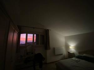een donkere kamer met een bed en een raam bij Affittasi a Capalbio per un minimo di 5 notti in Capalbio