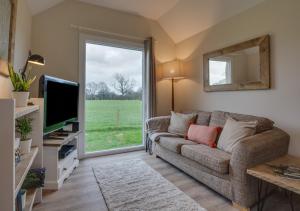 un soggiorno con divano e TV di The Bolthole a Biddenden