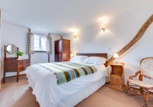 een slaapkamer met een groot wit bed en een stoel bij The Bothy in Biddenden