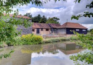 a group of buildings next to a river at The Cowshed in Herstmonceux