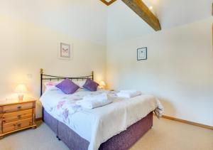a bedroom with a large bed with purple pillows at The Cowshed in Herstmonceux