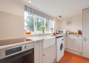 a kitchen with white cabinets and a washer and dryer at The Little House in Rolvenden