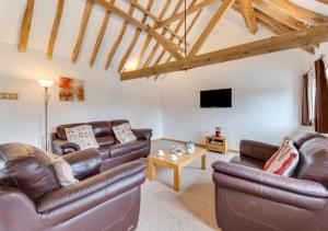 a living room with leather couches and a tv at The Parlour in Brede