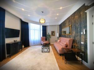 uma sala de estar com um sofá rosa e uma televisão em Historic Apartment, very close to the beach and main activities em Constança