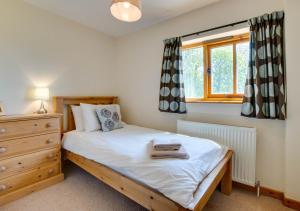 a bedroom with a bed and a dresser and a window at The Old Granary in Brede