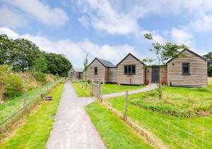 a dirt road leading to a row of wooden houses at The Warren in Biddenden