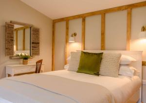 a bedroom with a white bed with a green pillow at Treetops at Bewl Water in Wadhurst