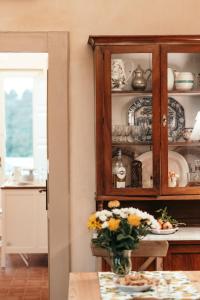 una cocina con un armario lleno de platos y un jarrón de flores en Puleera Boutique Hotel en San Leonardello