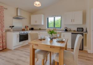 uma cozinha com uma mesa de madeira e cadeiras numa cozinha em The Stables at Skelcrosse em Hawkhurst