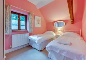 two beds in a room with pink walls at Valley View Barn in Hartfield
