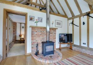 a living room with a brick fireplace and a tv at Wagon Lodge at Forstal Farm in Tenterden