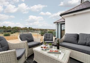 a patio with wicker furniture and a table and chairs at Vause at Sea in Kingsdown