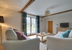a living room with two chairs and a tv at Well Cottage in Barham