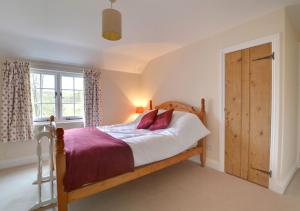 a bedroom with a wooden bed and a window at Well Cottage in Barham