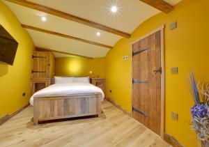 a bedroom with yellow walls and a bed with a wooden door at Vineyard Hollow in Bodiam