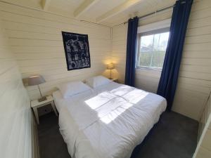 een slaapkamer met een groot wit bed en een raam bij d'Oude Herbergh, vakantiehuizen aan het water in Terherne