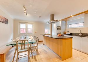 uma cozinha com uma mesa de jantar e uma cozinha com armários brancos em York Mansions Apartment em Broadstairs