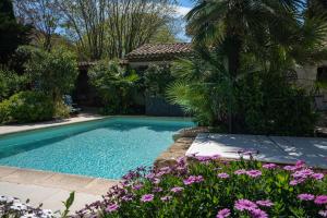 - une piscine dans une cour ornée de fleurs violettes dans l'établissement Oasis centre charme, à Montpellier