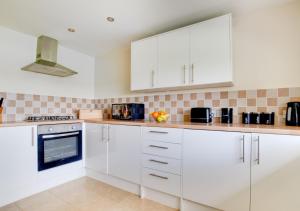 a white kitchen with white cabinets and appliances at Walnut Cottage in Swingfield