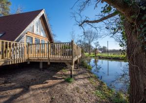 a house with a deck next to a river at Waterside Lodge in Bodiam