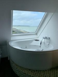 La salle de bains est pourvue d'une baignoire et d'une grande fenêtre. dans l'établissement DUPLEX AVEC JACUZZI vue imprenable sur la baie de Wissant, à Wissant