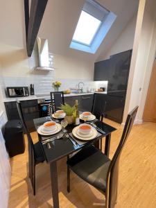 a dining room with a black table and chairs at Brand New! Stunning, Stylish, Cosy Apartment in Centre of Saffron Walden in Saffron Walden