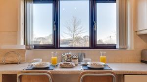 a kitchen with a table with plates of food and two windows at Elm Croft in Old Brampton