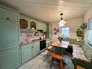 a kitchen with green cabinets and a wooden table at Maisonette-FeWo Fritz mit Infrarotsauna in Großschönau