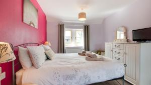 een slaapkamer met een bed met een roze muur bij Farriers Cottage in Ilam
