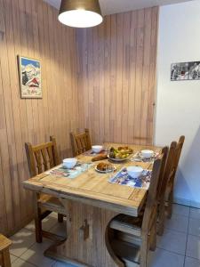 uma mesa de madeira com cadeiras e uma taça de fruta em Appartement Les Orres 1800 - Vue montagne em Les Orres