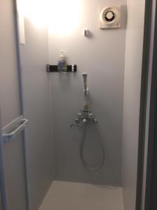 a bathroom with a shower with a hose on the wall at Accommodation Service B&B in Miyazaki
