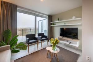 a living room with a large window and a television at Belcasa Family Suites & Lofts in Middelkerke