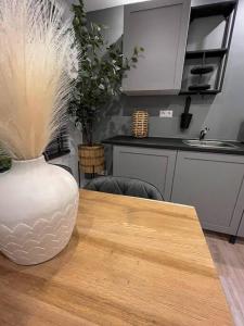 Gezellig appartement, Gerenoveerd eind 2022 في تيلبورغ: وجود مزهرية بيضاء على طاولة خشبية في مطبخ