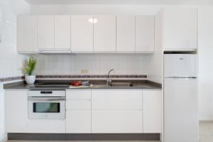 a white kitchen with white cabinets and a sink at Callao Beach 3 in Arrieta +14 photos