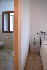 a bedroom with a bed and a bathroom with a toilet at Le Mimose in Pulsano