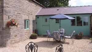 a patio with a table and chairs and an umbrella at Field Barn in Matlock