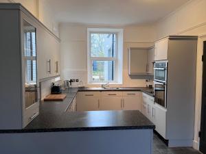 a kitchen with white cabinets and a black counter top at Tregwylan in Nefyn