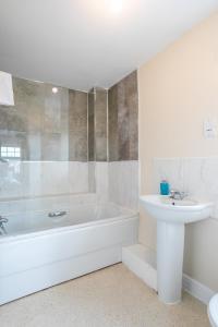 a white bathroom with a tub and a sink at Durham Heights in Leyland