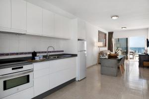 una cocina con armarios blancos y una mesa en una habitación en Callao Beach 6, en Arrieta