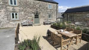 a patio with a table and chairs in front of a building at Golconda Cottage in Brassington